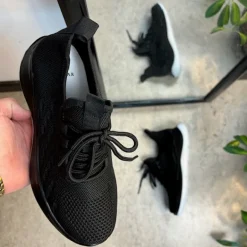 Sorte strikkede slip on sko med en fast kant i åbningen.